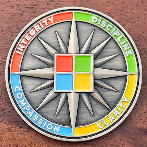 Round coin with four sections in red, green, yellow and blue. Four squares in the center with same colors on antique silver star background.
