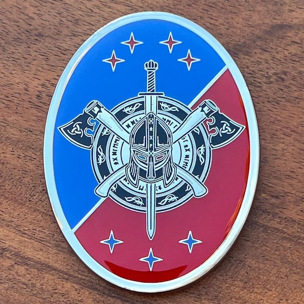 Oval challenge coin featuring crossed axes, a sword and a battle helmet