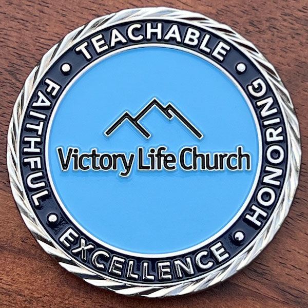 Round silver challenge coin representing Victory Life Church. 