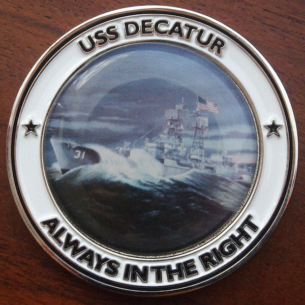Round polished silver challenge coin representing the USS Decatur. 