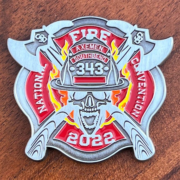 A custom-shaped silver challenge coin for the 2022 National Fire Convention.