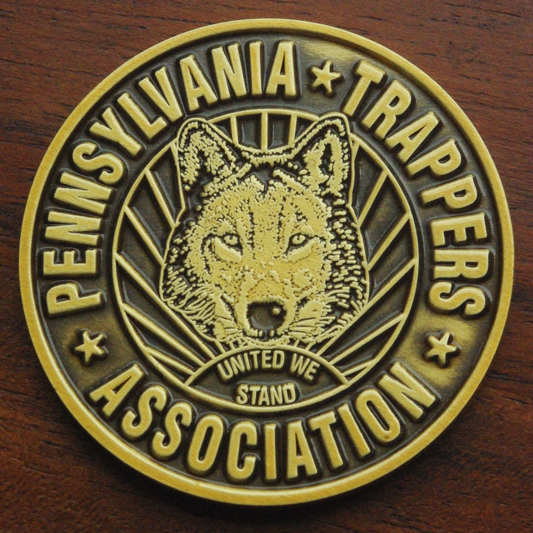 Round antique gold challenge coin representing the Pennsylvania Trappers Association