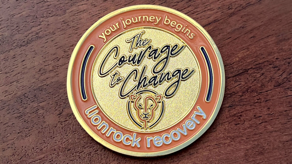Polished gold coin representing lionrock recovery, center image "The courage to change" with a lion's head
