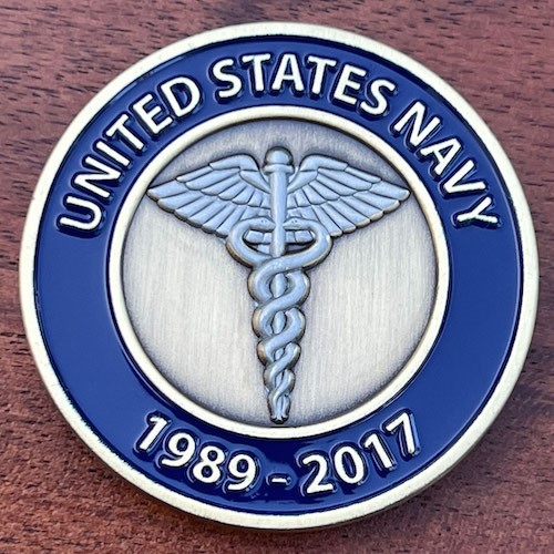 Round Navy challenge coin with caduceus in center, surrounded by wide blue border and narrow white border