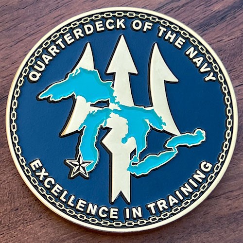 Round Navy challenge coin with trident on blue background and overlay of the Great Lakes