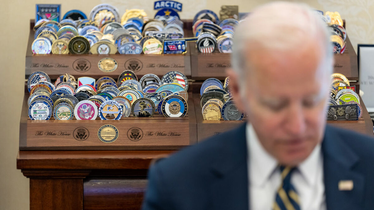 President Biden in front of his challenge coin collection in the White House