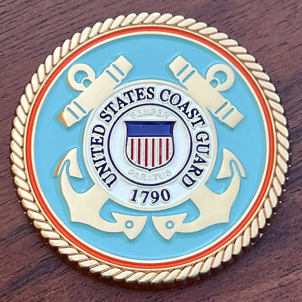 A round gold challenge coin representing the U.S. Coast Guard. 