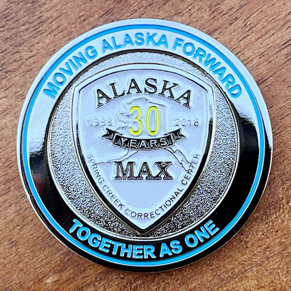 Round polished silver challenge coin belonging to Spring Creek Correctional Center in Seward, Alaska. 