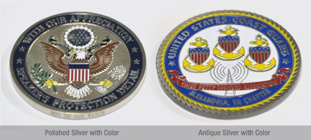 two round challenge coins side by side. The left one features polished silver with color, and the right one features antique sliver with color
