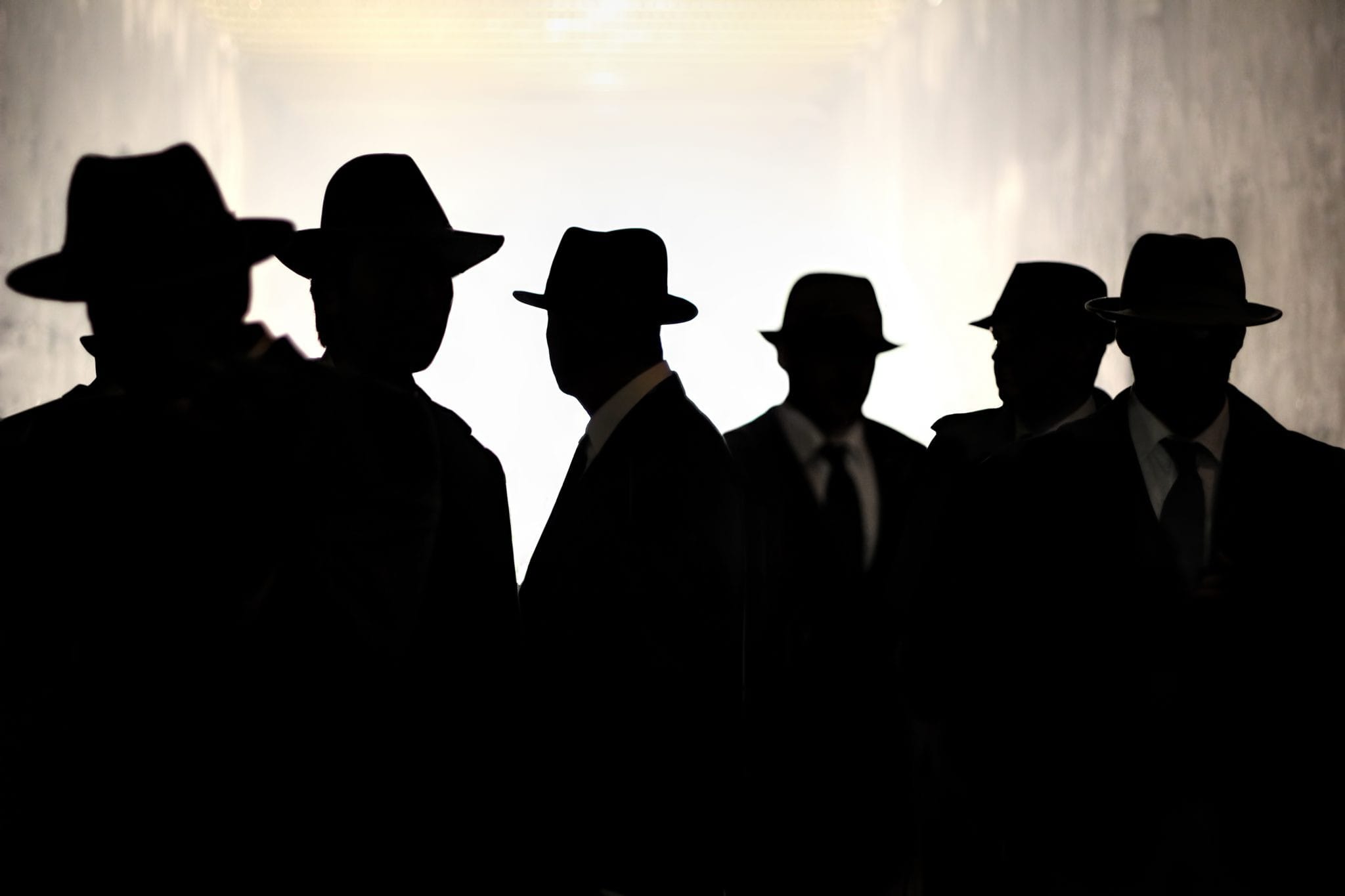 Silhouette of six men wearing identical hats and dark clothing